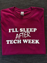 Load image into Gallery viewer, A folded magenta t-shirt with white text reading 'I'LL SLEEP AFTER TECH WEEK' laid flat on a dark gray textured fabric background.